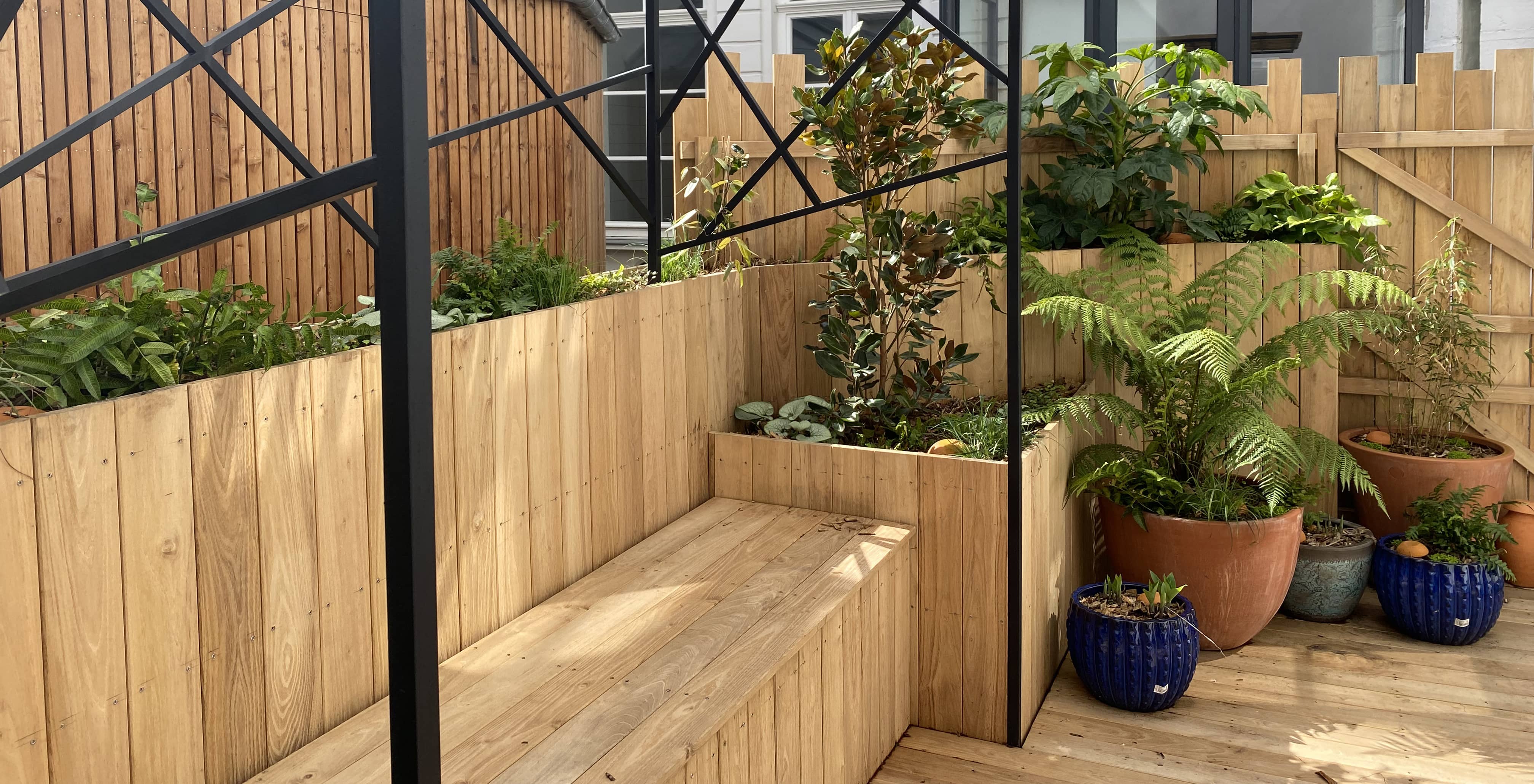 Terrasse en bois aménagée avec une pergola et des plantations